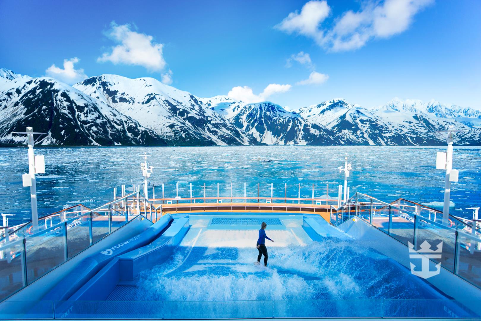 View of woman surfing on the FlowRider with Alaskan mountains in the background